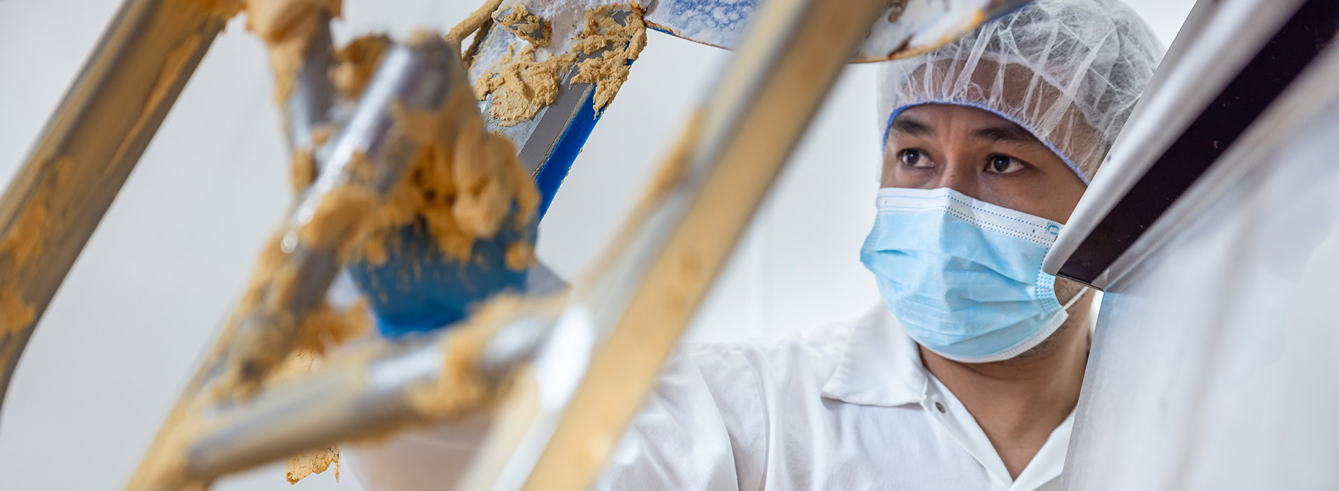 Illustrative bakery worker attending to production equipment